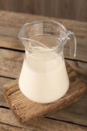 Jug of fresh milk on wooden table