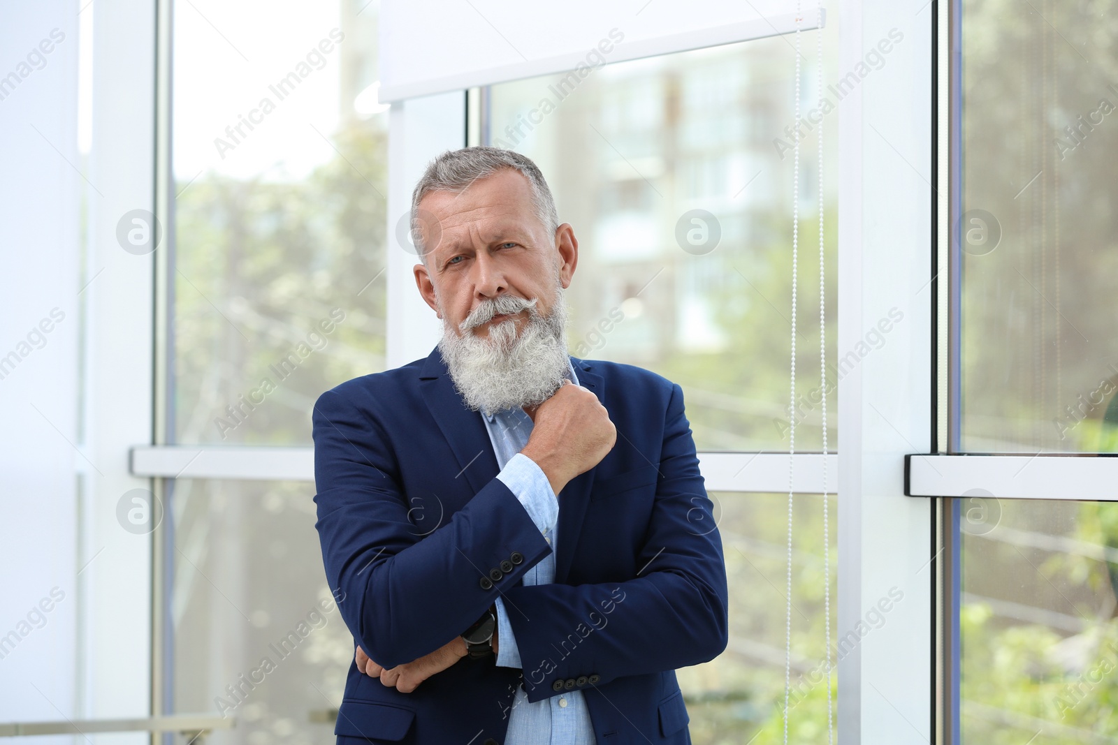 Photo of Portrait of handsome mature man in elegant suit near window