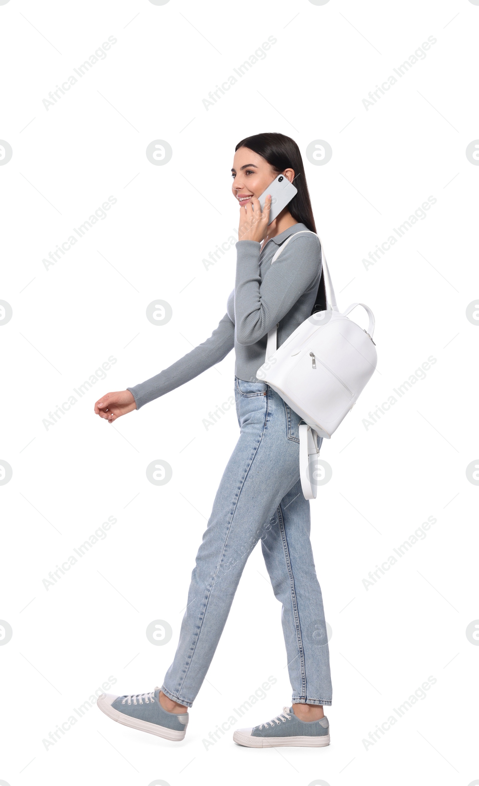 Photo of Young woman talking on smartphone while walking against white background