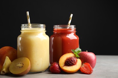 Photo of Delicious juices and fresh ingredients on grey table against black background