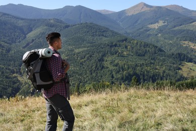 Photo of Tourist with backpack enjoying view in mountains on sunny day