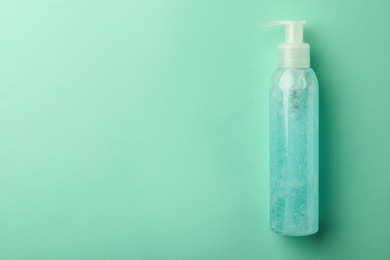 Photo of Bottle of cosmetic gel on turquoise background, top view. Space for text