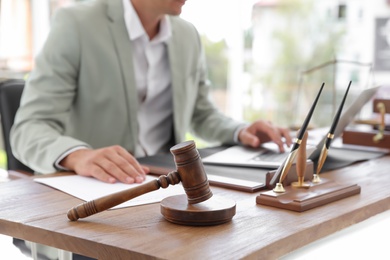 Photo of Wooden gavel and blurred notary with laptop on background
