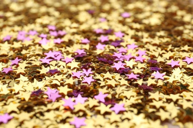 Photo of Golden and purple confetti stars as background, closeup. Christmas celebration