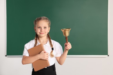 Photo of Pupil with school bell near chalkboard in classroom, space for text