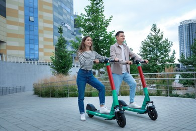 Photo of Happy couple with modern electric kick scooters on city street