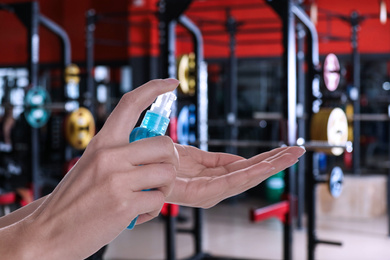 Image of Woman applying antiseptic gel at gym, closeup. Preventive measures during epidemic period 