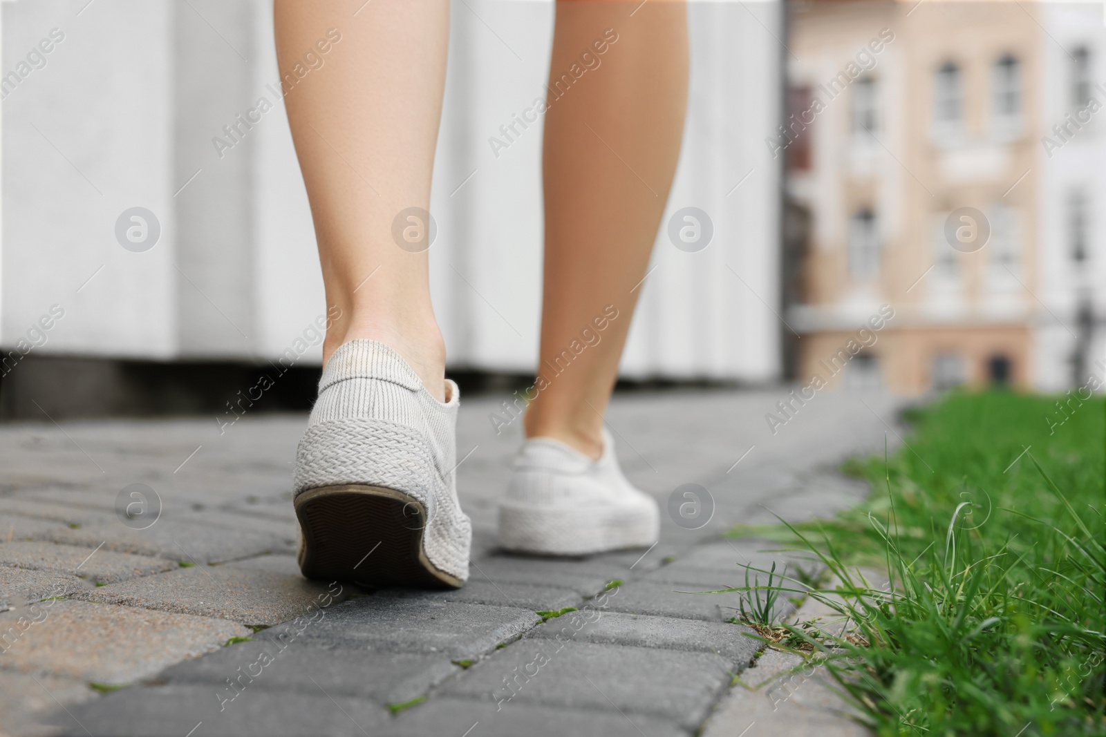 Photo of Woman in stylish sneakers walking on city street, closeup. Space for text