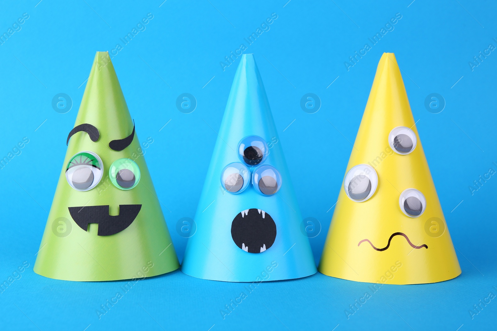 Photo of Spooky paper monsters on light blue background. Halloween decoration