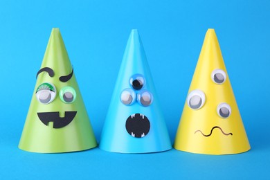 Photo of Spooky paper monsters on light blue background. Halloween decoration