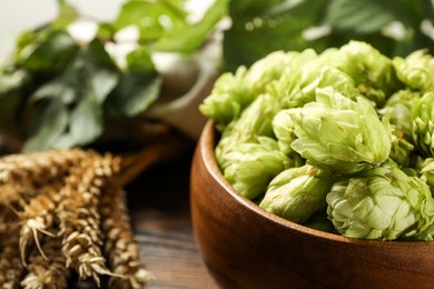 Photo of Fresh hop flowers and wheat ears on wooden table, closeup