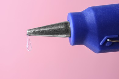 Dripping hot glue from gun on pink background, closeup