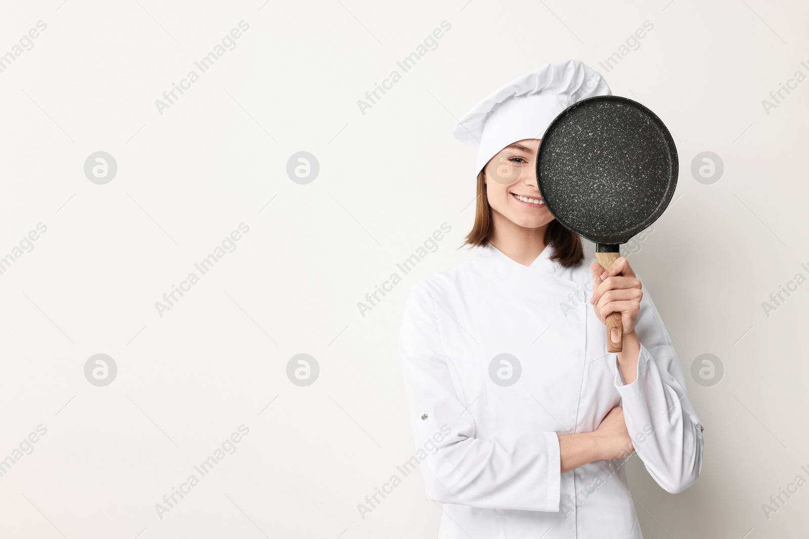 Photo of Professional chef with frying pan on light background. Space for text