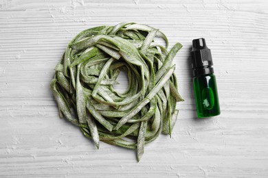 Photo of Green pasta, bottle of food coloring and flour on white wooden table, flat lay