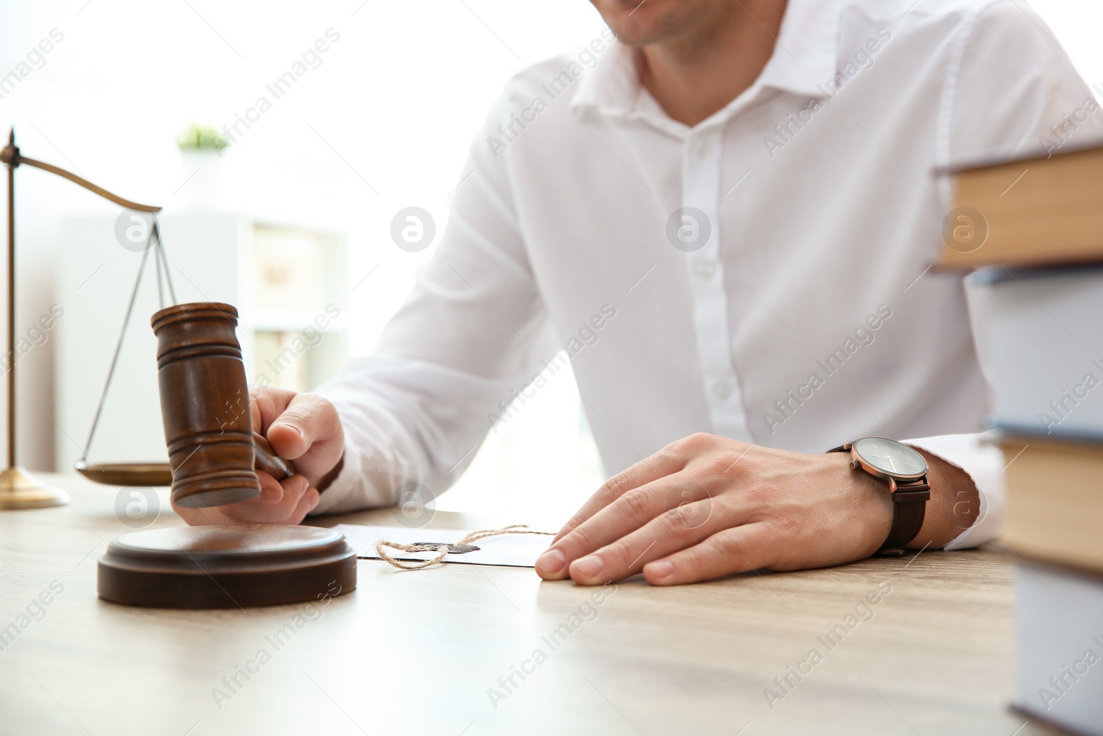 Photo of Judge with gavel at table in courtroom, closeup. Law and justice concept