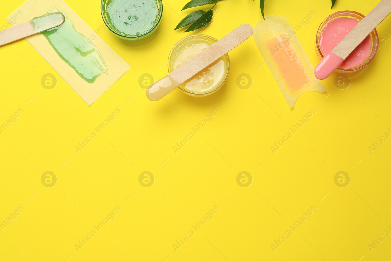 Photo of Flat lay composition with different types of wax and spatulas on yellow background. Space for text