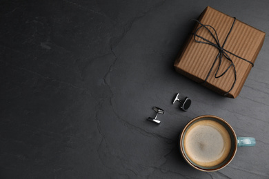 Photo of Cup of coffee, gift box and cuff links on black table, flat lay with space for text. Happy father's day
