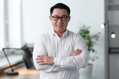 Portrait of smiling businessman with crossed arms in office