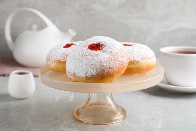 Photo of Pastry stand with delicious jelly donuts on grey table