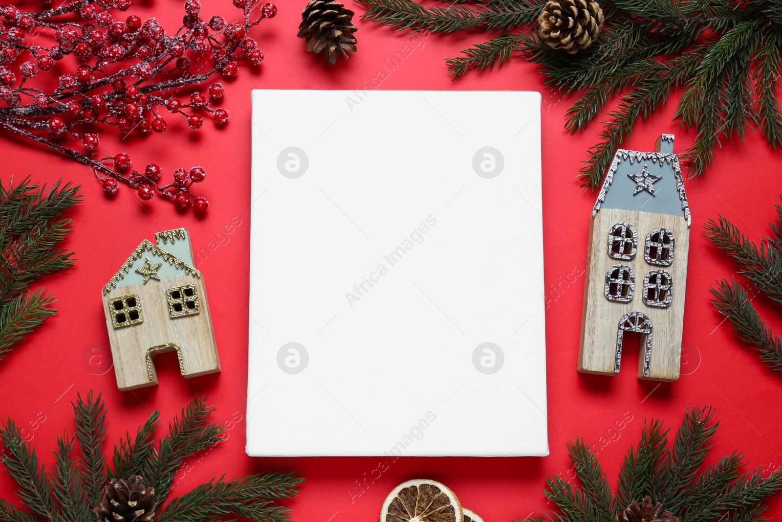 Photo of Blank canvas and Christmas decor on red background, flat lay. Space for design