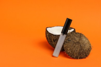 Photo of Tube of eyelash oil and fresh coconut on orange background. Space for text