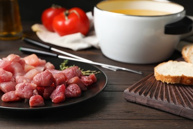 Photo of Plate with raw meat fondue pieces on table, closeup