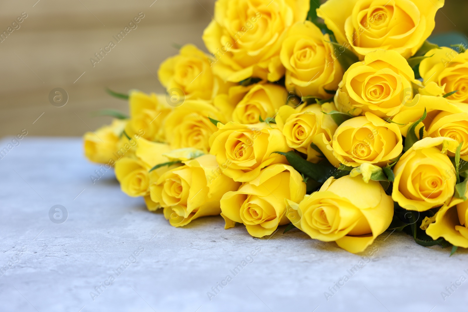 Photo of Beautiful bouquet of yellow roses on light table, selective focus. Space for text