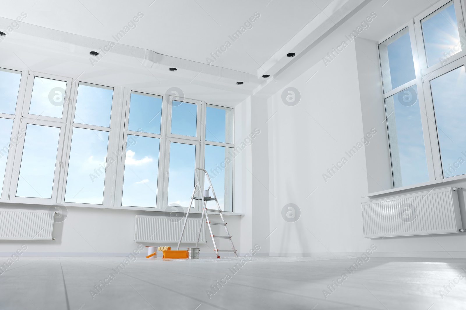 Photo of Stepladder and painting tools near window in empty room, space for text