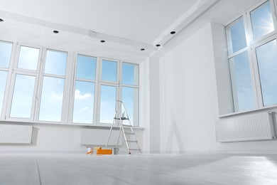 Photo of Stepladder and painting tools near window in empty room, space for text