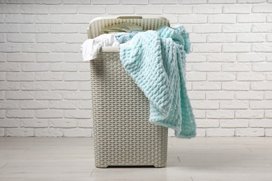 Photo of Laundry basket with clothes near white brick wall