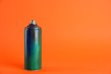 Photo of Used can of spray paint on orange background. Space for text