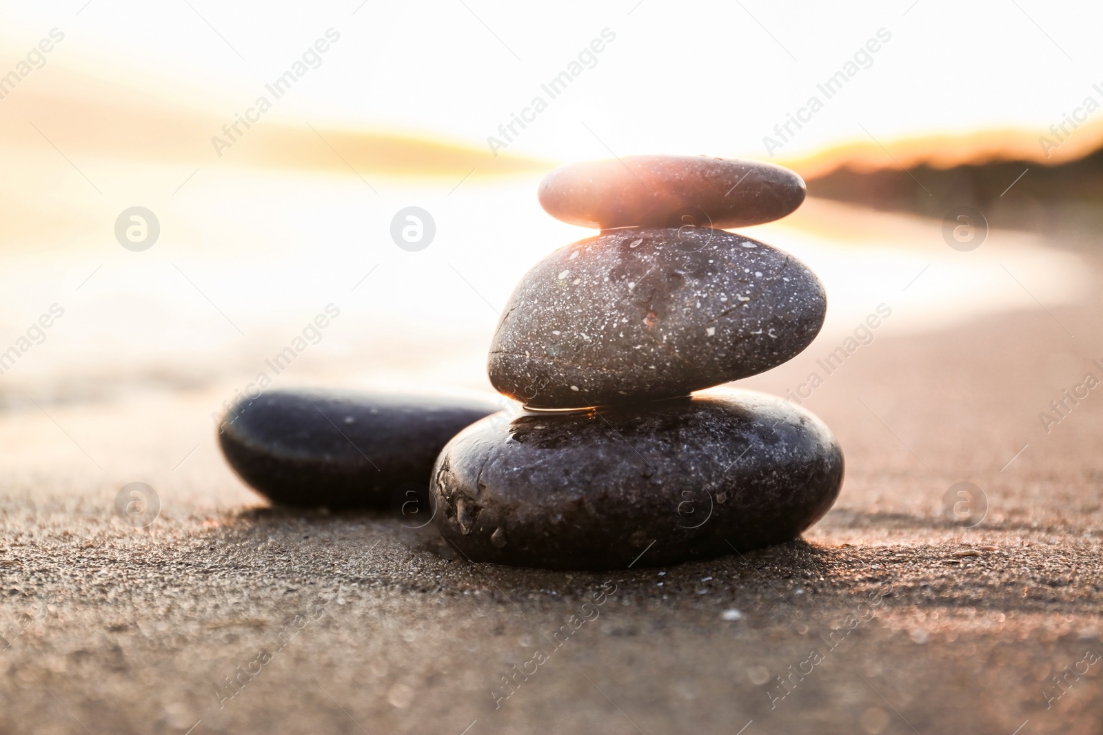 Photo of Dark stones on sand near sea at sunset. Zen concept