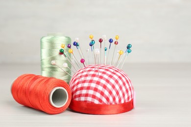 Pin cushion and coils of threads on light beige table