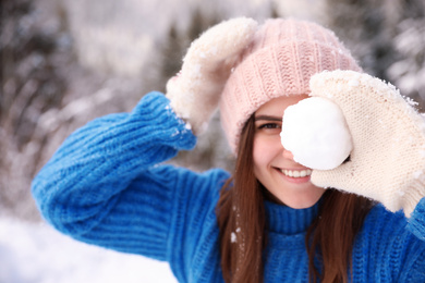 Young woman with snowball outdoors. Winter vacation