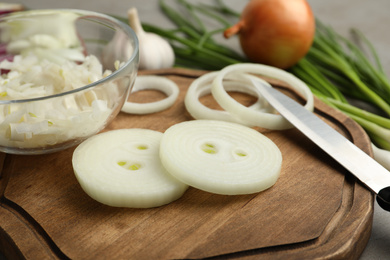 Photo of Fresh onion and knife on wooden board, closeup