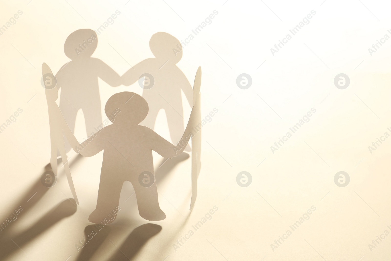 Photo of Paper people holding hands on light background. Unity concept