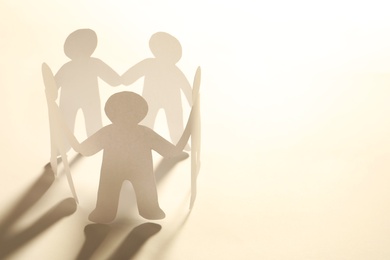 Photo of Paper people holding hands on light background. Unity concept