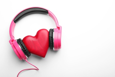 Photo of Decorative heart and modern headphones on white background, top view