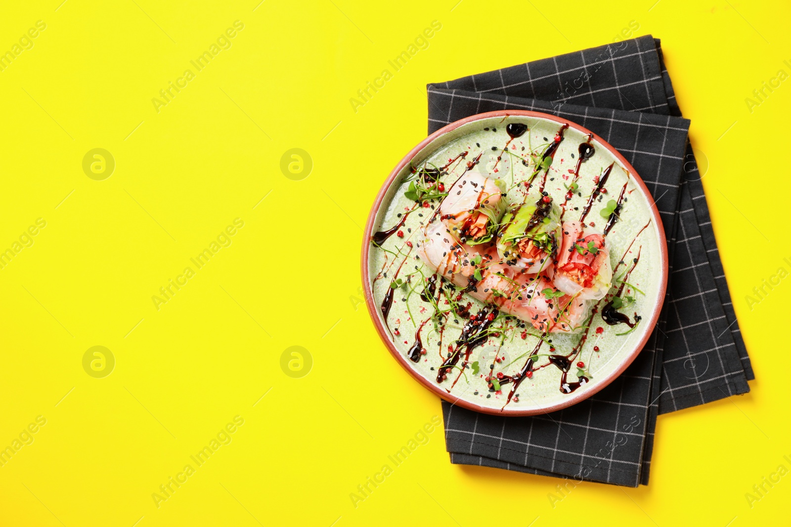 Photo of Delicious spring rolls with sauce and microgreens on yellow background, top view. Space for text