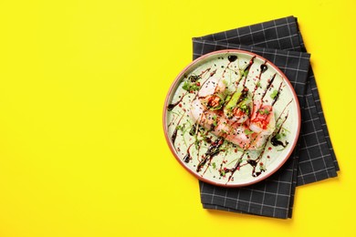Delicious spring rolls with sauce and microgreens on yellow background, top view. Space for text