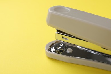 Photo of Beige stapler on yellow background, closeup. Space for text