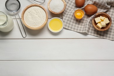 Ingredients for crepes on white wooden table, flat lay. Space for text