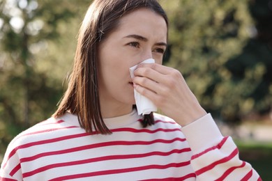 Photo of Woman with napkin suffering from seasonal allergy outdoors