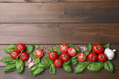 Photo of Flat lay composition with fresh basil leaves and vegetables on wooden table. Space for text