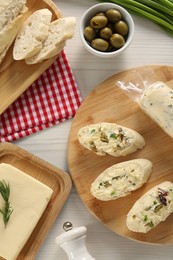 Photo of Tasty butter, olives, green onion and bread on wooden table, flat lay