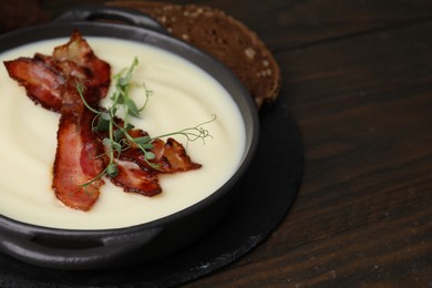 Photo of Delicious potato soup with bacon and microgreens in bowl on wooden table, closeup. Space for text