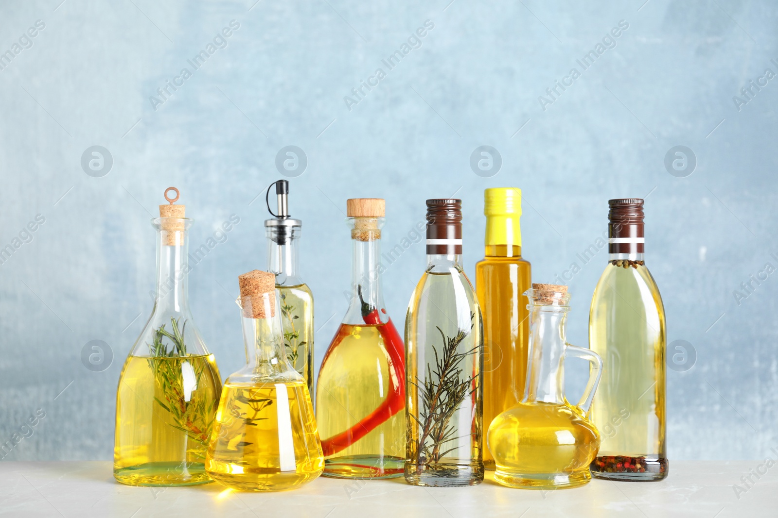 Photo of Different sorts of cooking oil in bottles on light grey table