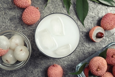 Fresh lychee juice and fruits on grey table, flat lay