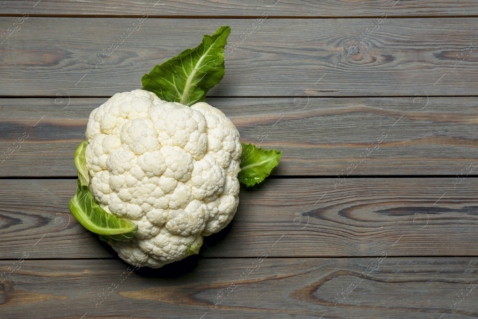 Photo of Whole fresh raw cauliflower on wooden table, top view. Space for text