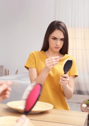 Photo of Young woman with brush indoors. Hair loss problem